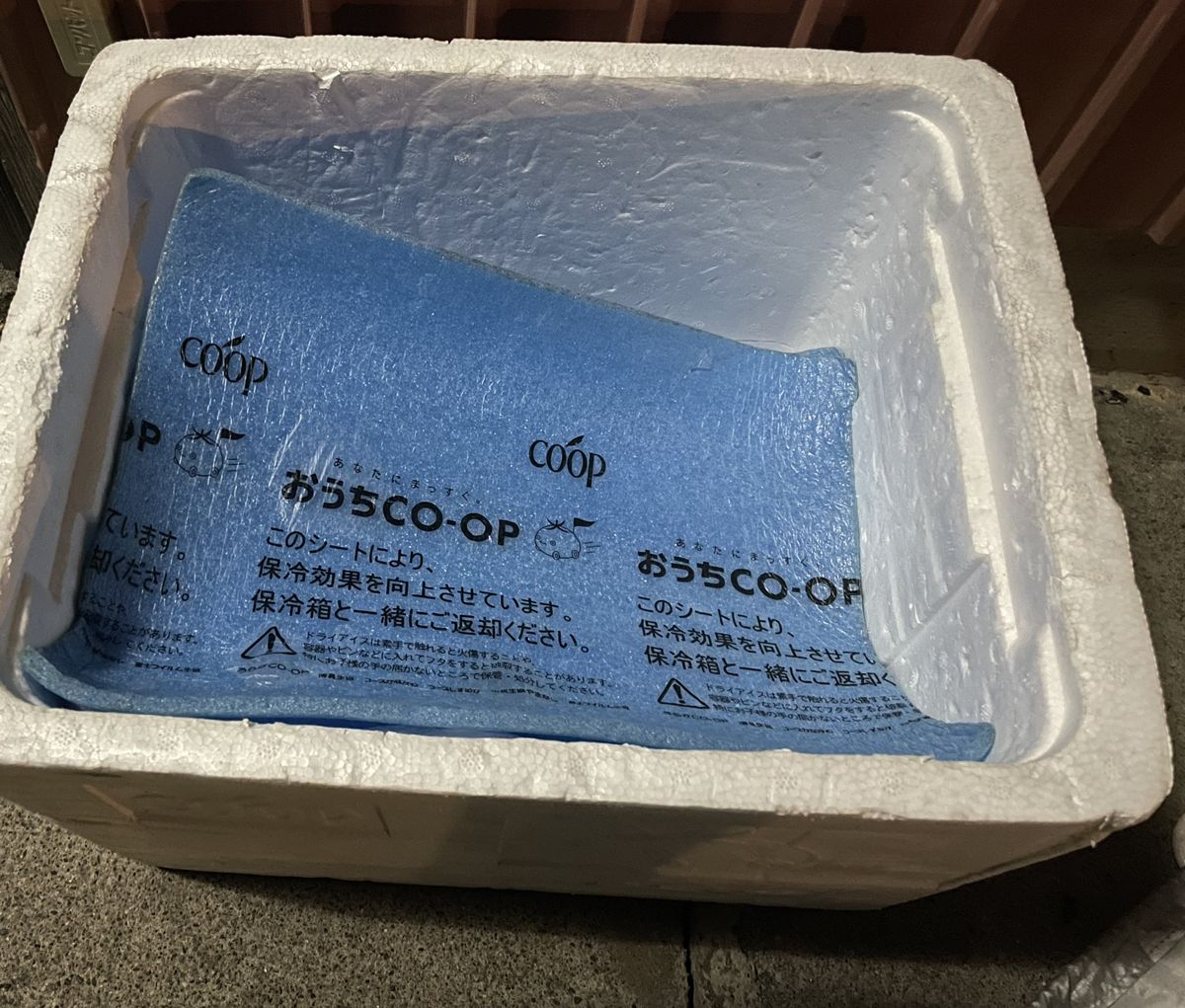 発泡スチロールの箱の中に入っている青い保冷シート